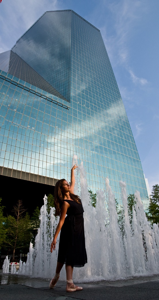 A person in a black dress touching a glass building

Description automatically generated