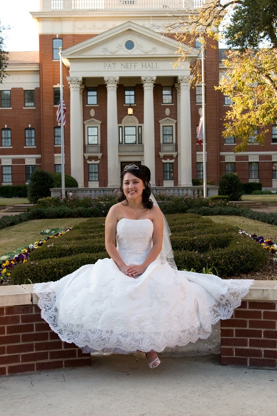 A person in a wedding dress sitting in front of a building

Description automatically generated
