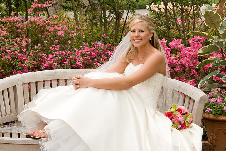 A person in a wedding dress sitting on a bench

Description automatically generated